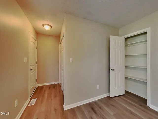 a view of an empty room with wooden floor and closet
