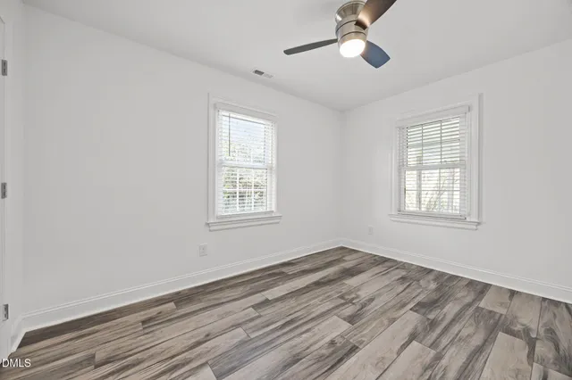 a view of empty room with wooden floor and fan