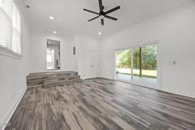 a view of empty room with wooden floor and fan