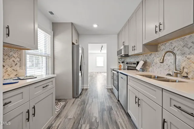 a kitchen with stainless steel appliances granite countertop a refrigerator a stove and a sink with wooden floor