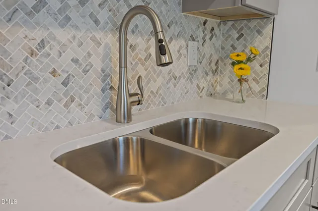 a kitchen with kitchen island granite countertop a sink cabinets wooden floor and stainless steel appliances