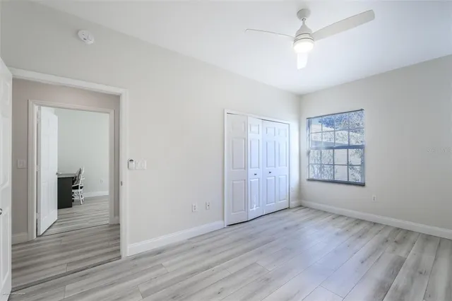 an empty room with wooden floor and a ceiling fan