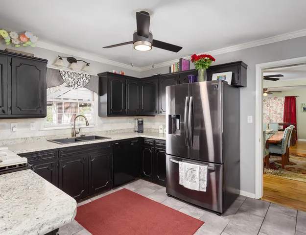 a kitchen with stainless steel appliances granite countertop a refrigerator a sink dishwasher a stove and a dining table with wooden floor