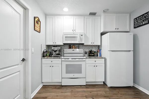 a kitchen with stainless steel appliances granite countertop a refrigerator a stove a sink and white cabinets