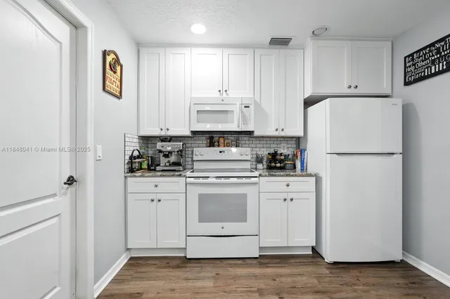a kitchen with white cabinets and sink