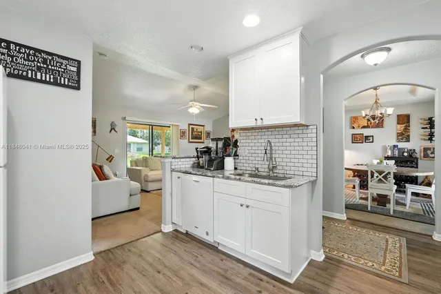 a kitchen with a refrigerator a stove a sink and white cabinets with wooden floor