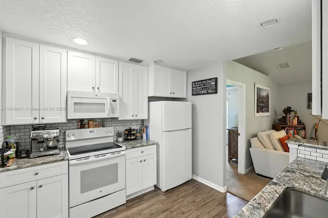 a kitchen with white cabinets and refrigerator