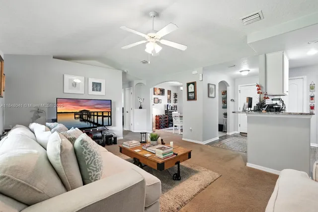 a living room with furniture and view of kitchen