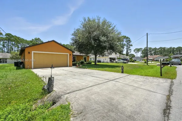 a view of a house with a yard and large tree