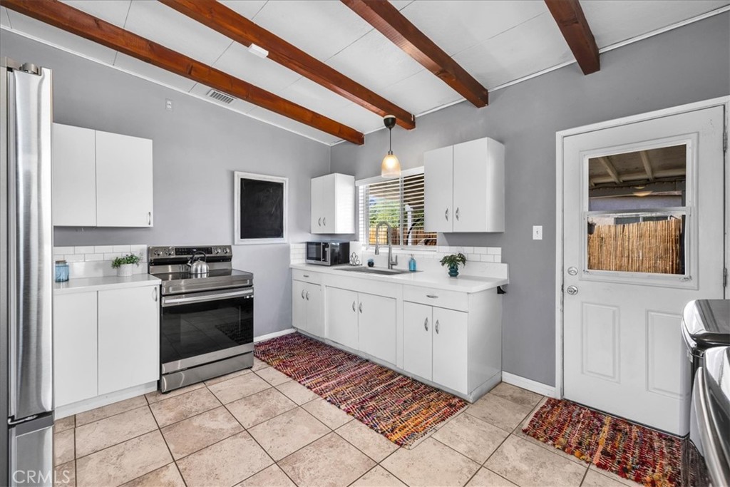 74825 Alta Loma Drive Twentynine Palms, CA 92277 - Photo 11 of 36 a kitchen with a stove top oven cabinets and a refrigerator