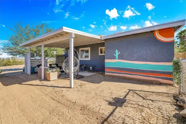 a backyard of a house with table and chairs under an umbrella