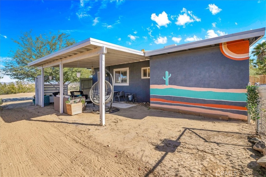 74825 Alta Loma Drive Twentynine Palms, CA 92277 - Photo 26 of 36 a backyard of a house with table and chairs under an umbrella