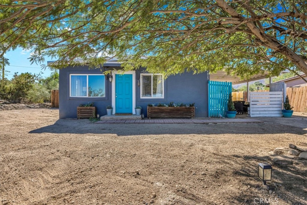 74825 Alta Loma Drive Twentynine Palms, CA 92277 - Photo 3 of 36 a view of a house with a yard tree and wooden fence