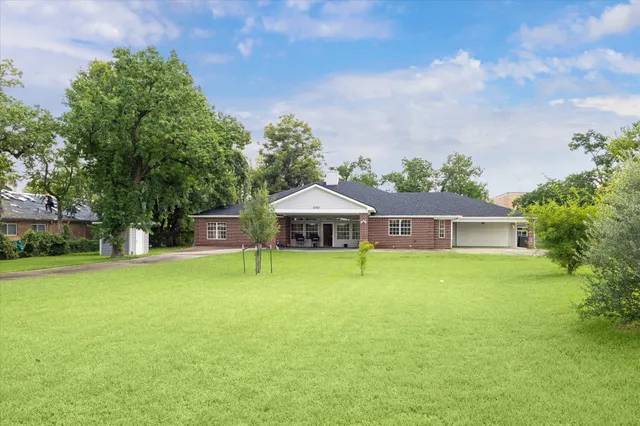 a yellow house with a big yard and large trees