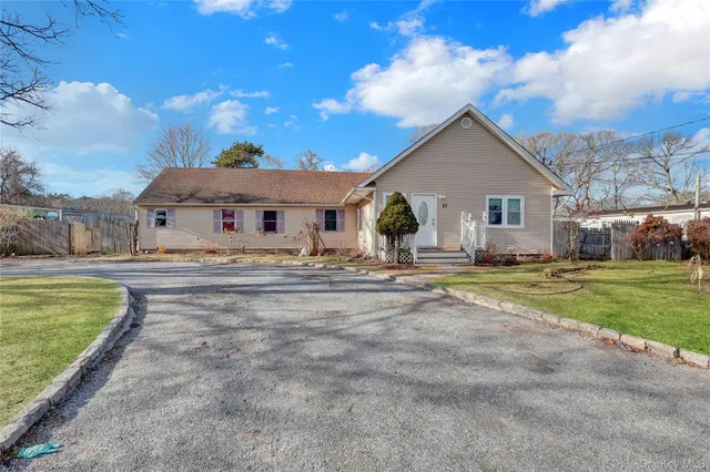 a view of a white house with a big yard and a large tree