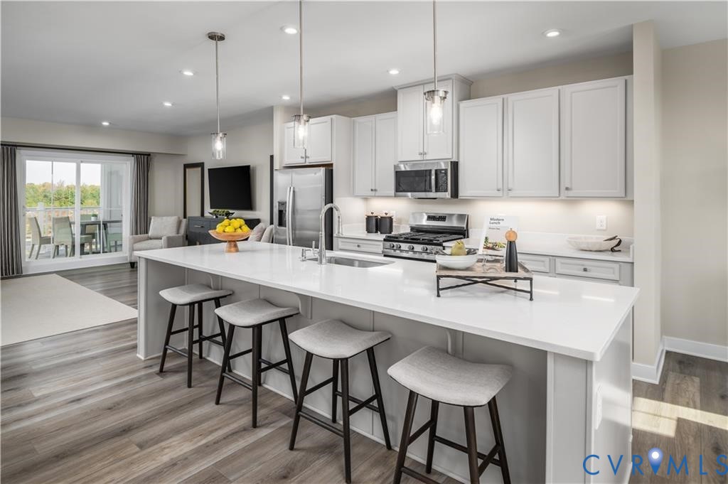 2806 Calgary Loop Chester, VA 23831 - Photo 5 of 20 a kitchen with stainless steel appliances a sink a stove a refrigerator a dining table and chairs with wooden floor