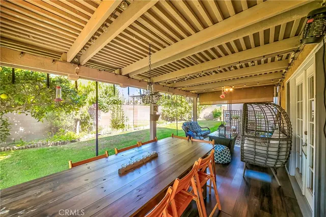 a view of a patio with table and chairs and wooden floor next to a yard