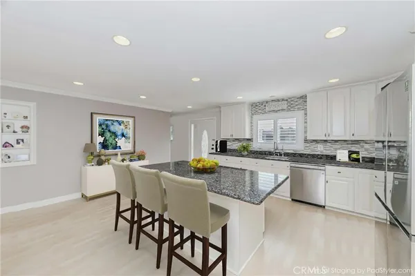 a kitchen with stainless steel appliances granite countertop a table and chairs in it