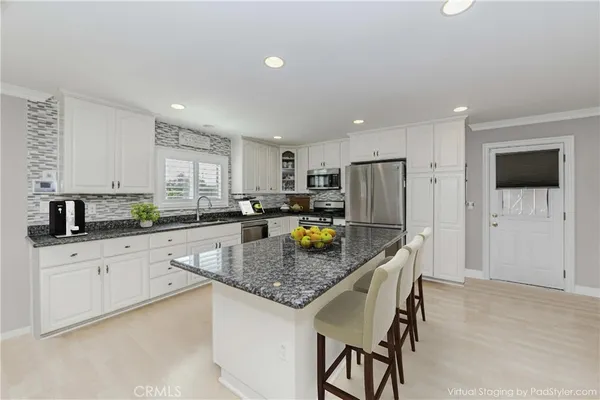 a kitchen with stainless steel appliances granite countertop a sink refrigerator and cabinets
