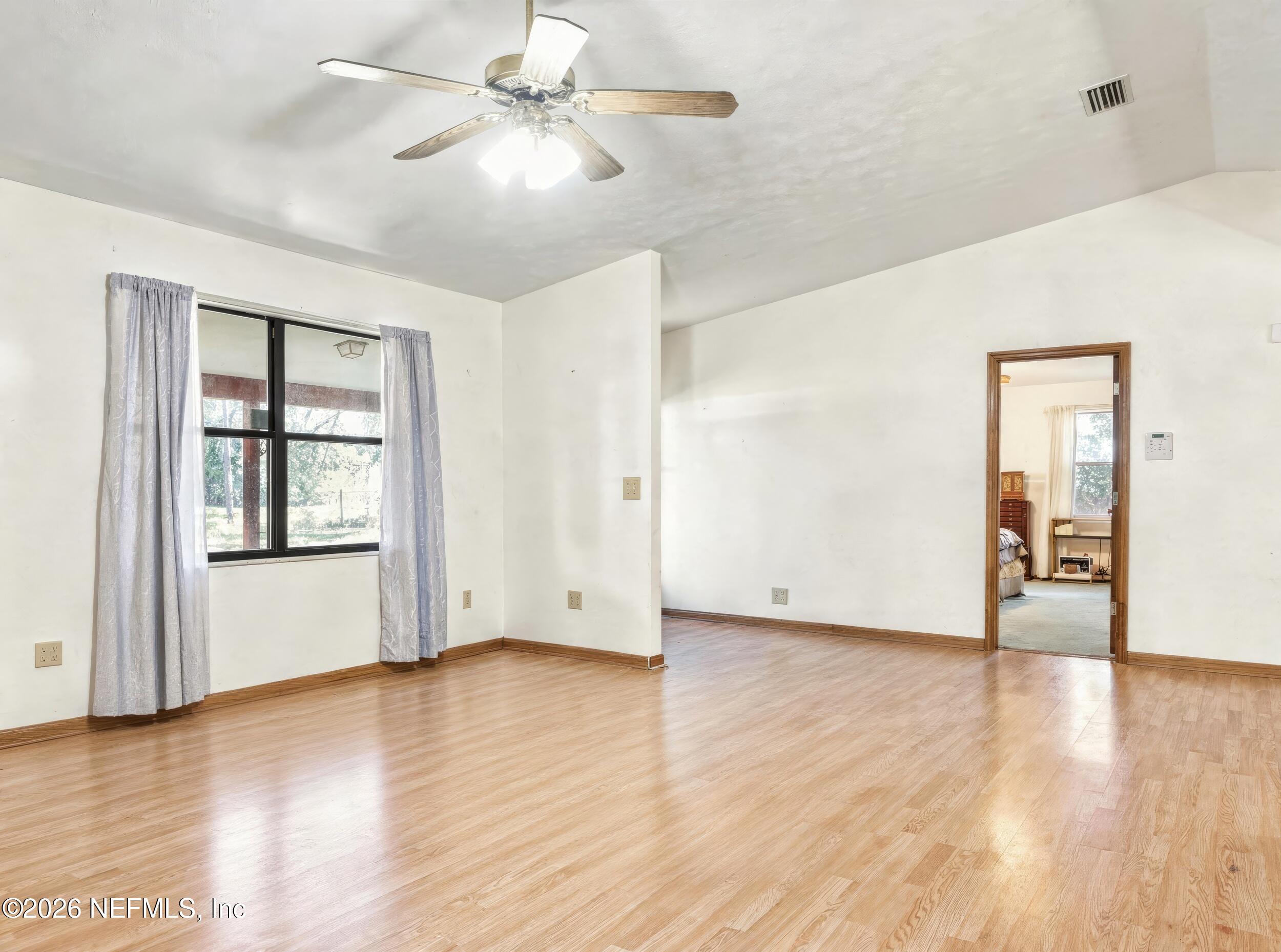 8336 Singleton Place Keystone Heights, FL 32656 - Photo 27 of 56 an empty room with wooden floor chandelier fan and windows