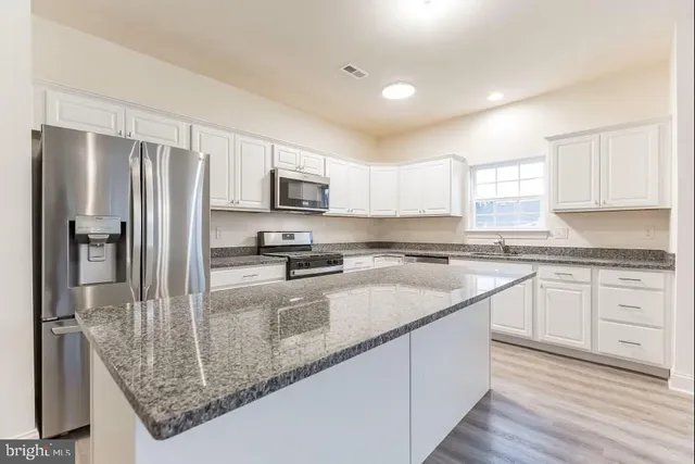 a kitchen with stainless steel appliances granite countertop a refrigerator a stove a sink and a granite counter tops