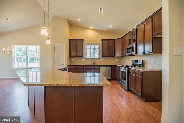 a kitchen with stainless steel appliances granite countertop a stove a sink and a microwave