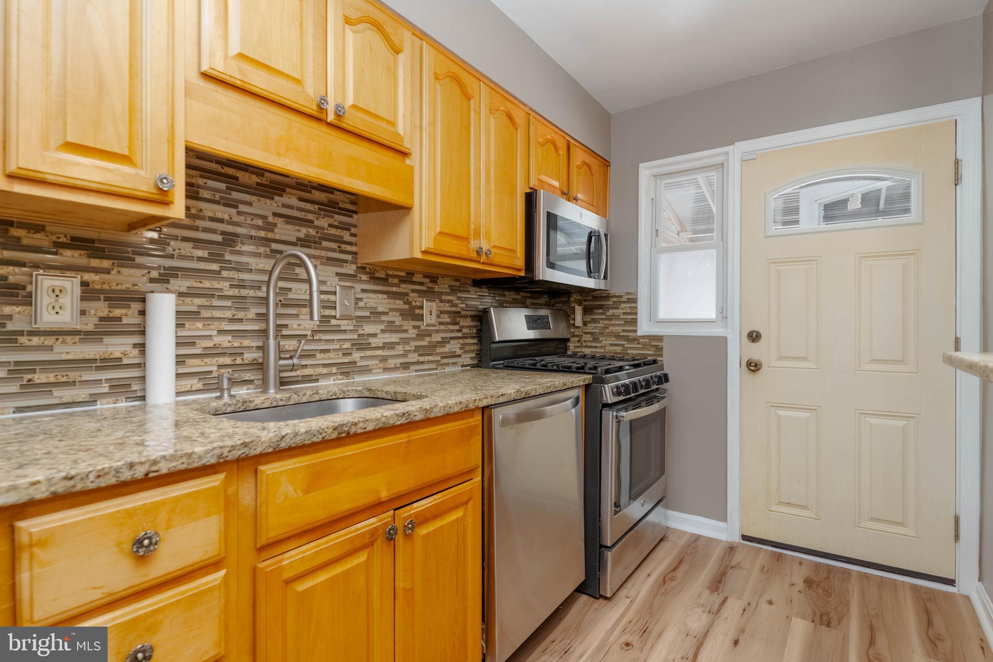 a kitchen with stainless steel appliances granite countertop a sink a stove and a refrigerator