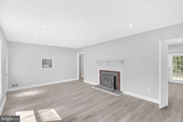 an empty room with wooden floor fireplace and windows