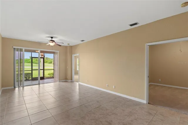 a view of an empty room with wooden floor and a ceiling fan