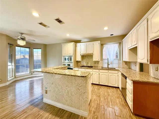 a kitchen with stainless steel appliances granite countertop wooden cabinets and a granite counter tops with a large window
