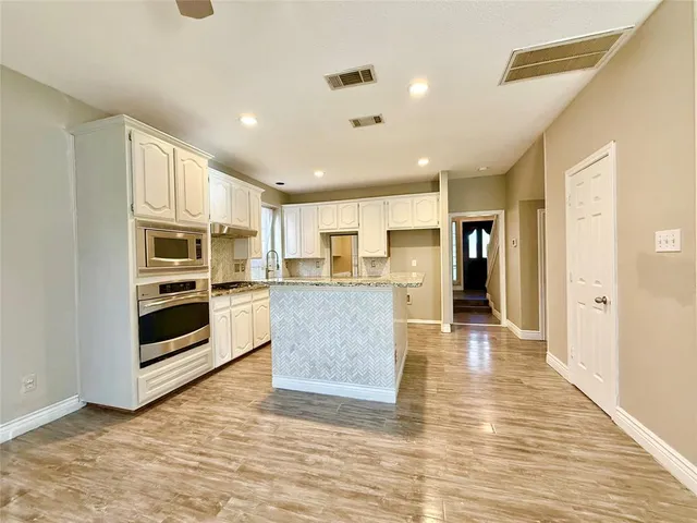 a view of kitchen with stainless steel appliances kitchen island wooden floor and living room