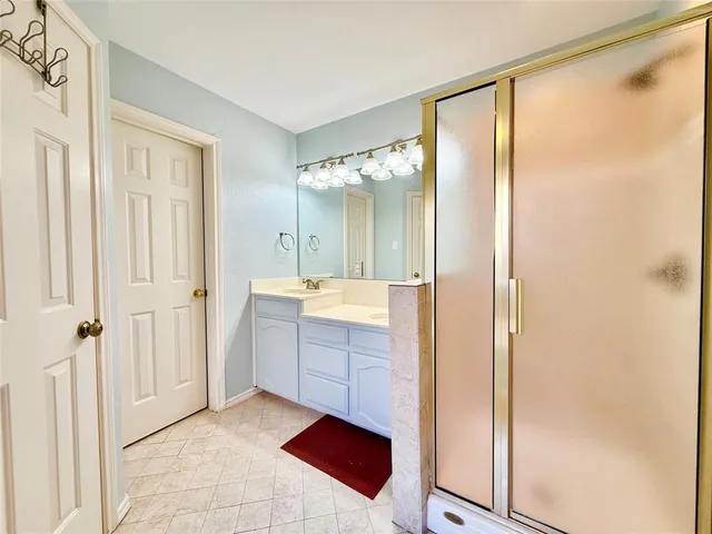 a bathroom with a double vanity sink mirror and shower