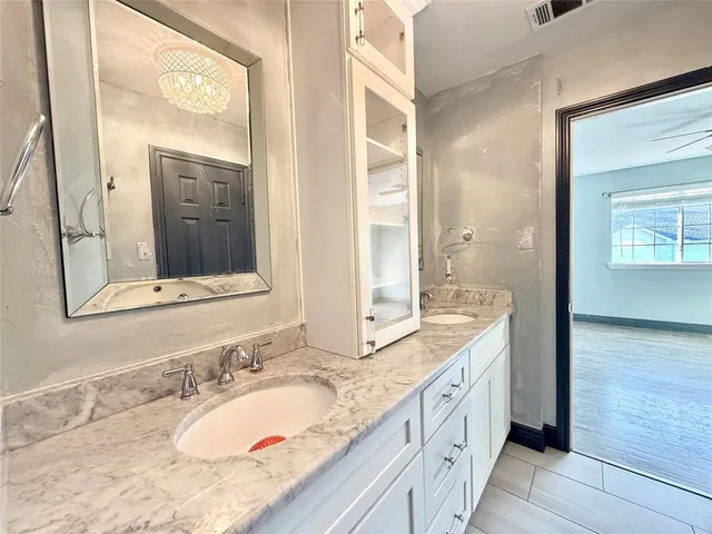 a bathroom with a granite countertop double vanity sink and a mirror