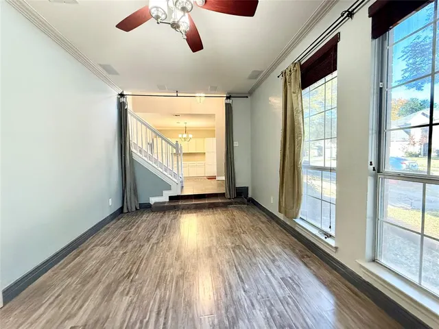 a view of an empty room with a window and wooden floor