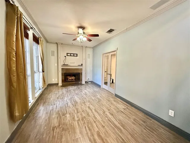 a view of a livingroom with a fireplace a ceiling fan and wooden floor