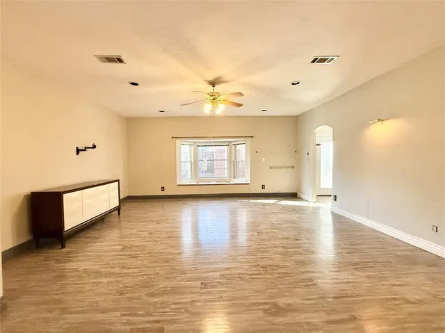 a view of an empty room with window and wooden floor