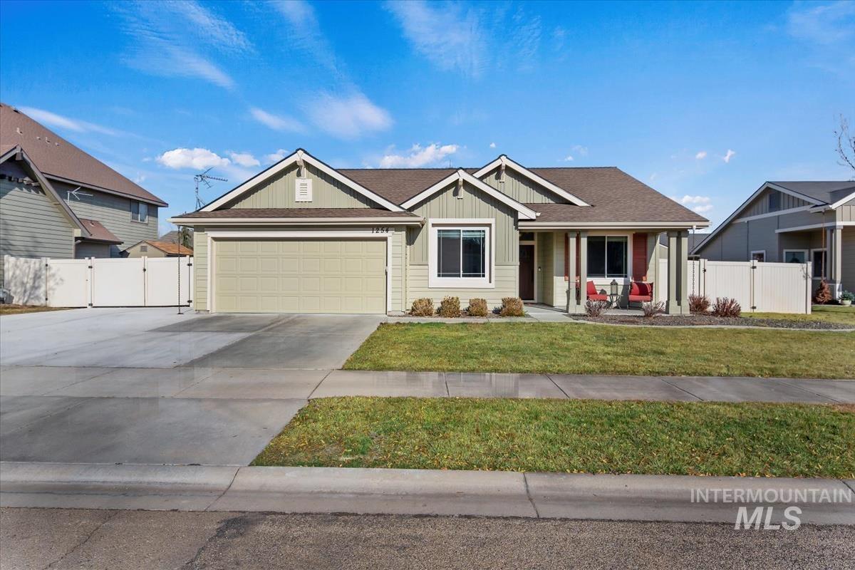 View of front of property featuring covered porch, a gate, concrete driveway, an attached garage, and board and batten siding