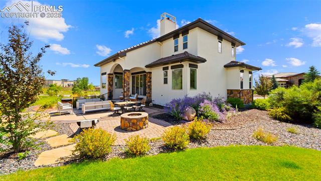 13625 Random Ridge View Colorado Springs, CO 80921 - Photo 42 of 50 Back of property with a patio area, stone siding, an outdoor living space with a fire pit, a chimney, and stucco siding