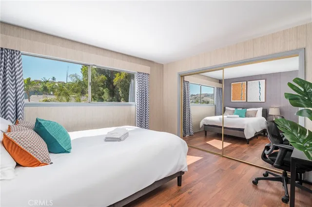 a bedroom with a bed a table and a dresser next to a window