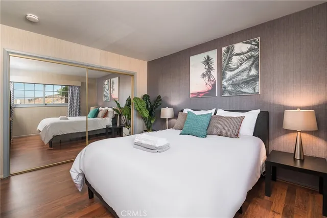 a bedroom with bed and a large mirror with wooden floor