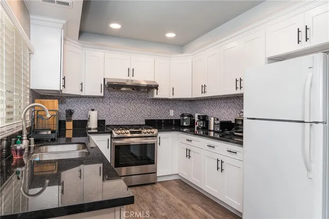 a kitchen with granite countertop a sink stove and refrigerator