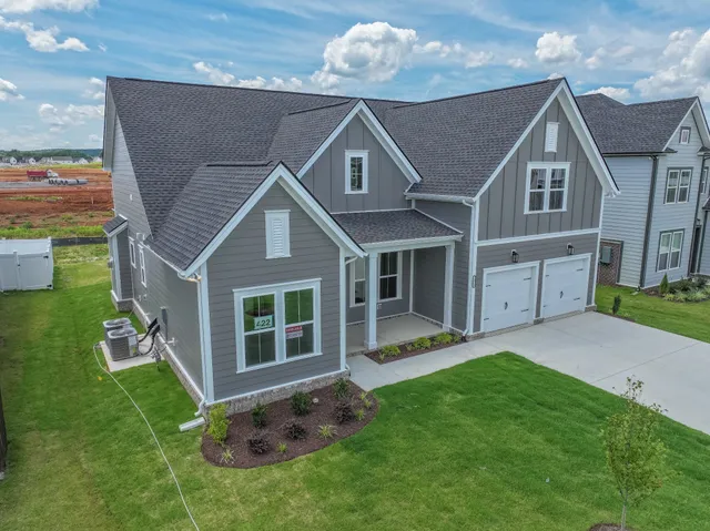 a view of a house with a big yard plants and large tree