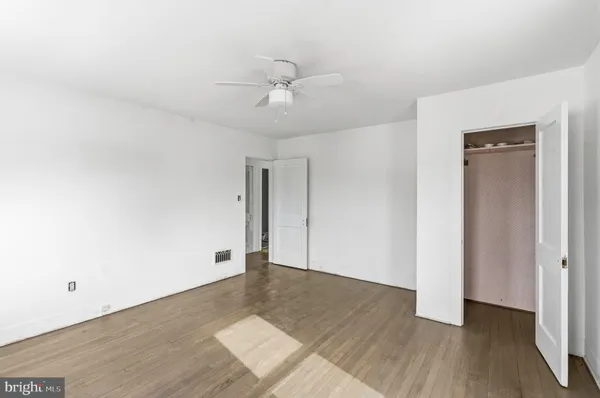 an empty room with wooden floor and ceiling fan