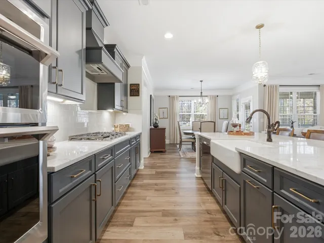 a large kitchen with stainless steel appliances granite countertop a lot of counter space and wooden floor