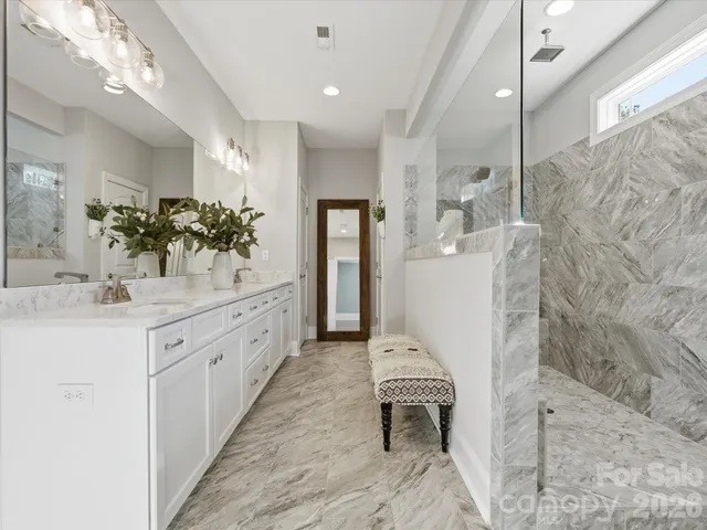 a bathroom with a double vanity sink a toilet a mirror and shower