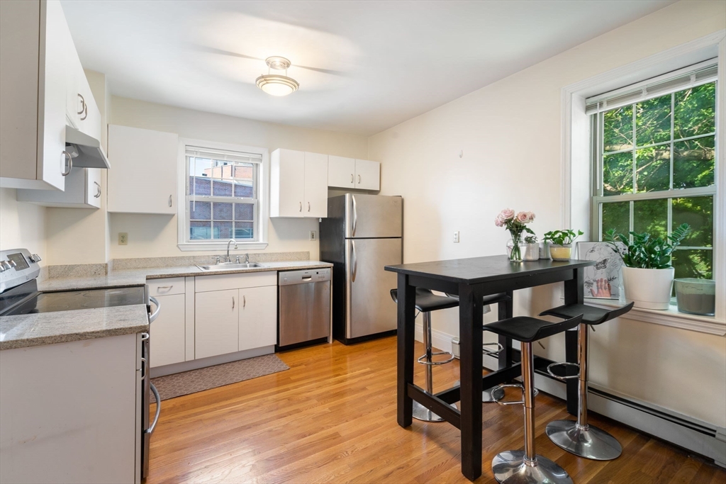 251 Roxbury Street, Unit 2 Boston, MA 02119 - Photo 3 of 16 a kitchen with a table chairs refrigerator and cabinets