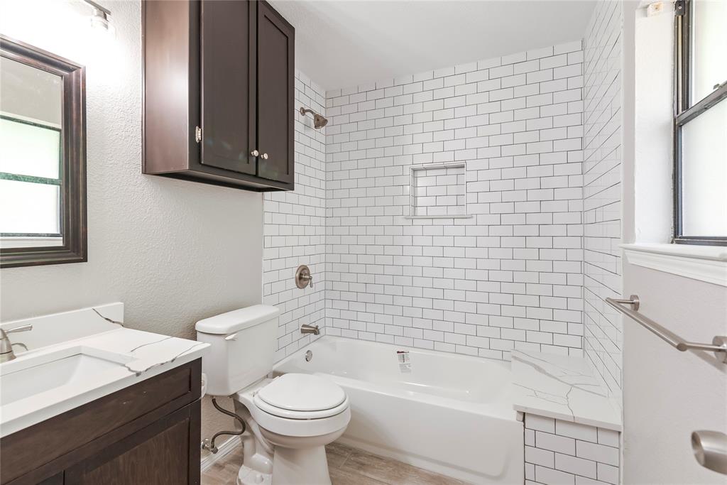 304 Moore Creek Road, Unit 300 Hurst, TX 76053 - Photo 14 of 17 Bathroom featuring a white subway tile shower surround with an integrated niche, a soaking tub, and a dark wood-finish vanity with a white countertop and integrated sink