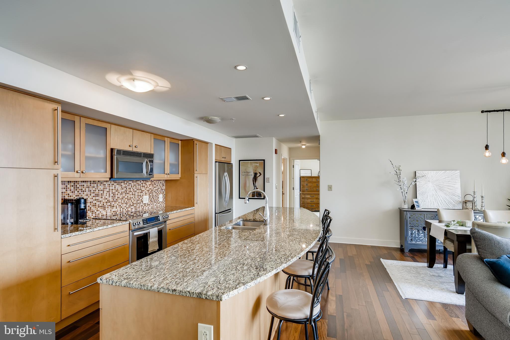 675 President Street, Unit 2105 Baltimore, MD 21202 - Photo 5 of 40 a kitchen with stainless steel appliances granite countertop a stove a sink dishwasher a dining table and chairs