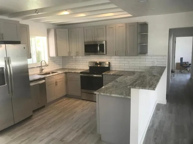 a kitchen with stainless steel appliances granite countertop a sink stove microwave and refrigerator