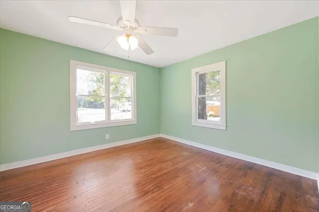 a view of an empty room with window and wooden floor